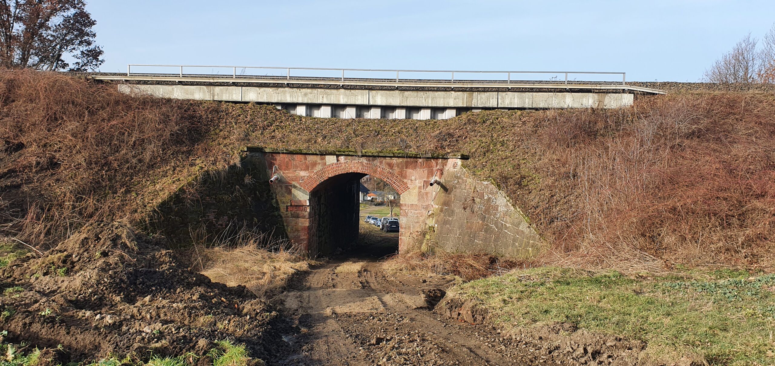 Ein alter Tunnel durch einen hohen Bahndamm.